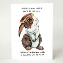 Load image into Gallery viewer, a greeting card, featuring an illustration of a brown and white rabbit with a pancake on its head. front reads, "I didn't know which card to get you / So here's a bunny with a pancake on its head"
