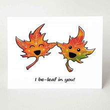 Load image into Gallery viewer, A greeting card with a graphic of two cartoon maple leaves with eyes and smiles, the card reads, "I be-leaf in you!", a pun on the word "believe"
