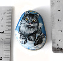 Load image into Gallery viewer, art of a silver gray maine coon cat as an angel, is hand painted on a river rock, and is available as either a keepsake, magnet or a pendant necklace
