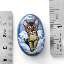 Load image into Gallery viewer, art of an Abyssinian cat, painted as an angel in the clouds. hand painted on a beach stone, available as a keepsake or pendant necklace
