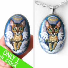 Load image into Gallery viewer, art of an Abyssinian cat, painted as an angel in the clouds. hand painted on a beach stone, available as a keepsake or pendant necklace
