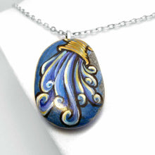 Load image into Gallery viewer, a beach stone hand painted with the symbol of Aquarius: the water bearer. available as a rock art keepsake, magnet or pendant necklace
