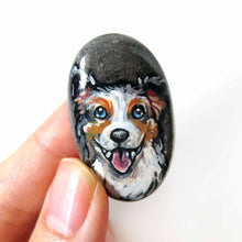 Load image into Gallery viewer, a small beach rock, hand painted with art of a smiling Australian Shepherd dog, available as a stone keepsake, fridge magnet, or pendant necklace. 
