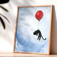 Load image into Gallery viewer, an art print with an illustration of a silhouette of a black cat, attached by the waist to a big red balloon, as it floats through a blue cloudy sky
