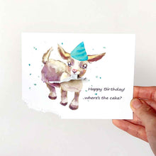 Load image into Gallery viewer, a greeting card featuring an illustration of a baby goat wearing a blue birthday hat, with the bottom left corner of the card hanging from its mouth. The card reads, Happy Birthday! .. where's the cake?
