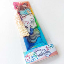 Load image into Gallery viewer, A PET (polyethylene terephthalate) bookmark and orange/yellow tassel, featuring a character from Rainbow of Crazy Comics: a ragdoll cat reads a book with a cat on the cover, as she lounges in a colourful box. on the bottom, it says @ Rainbowofcrazy

The bookmark is packaged in a sleeve with a small band with the text "Rainbow of Crazy Comics bookmark"
