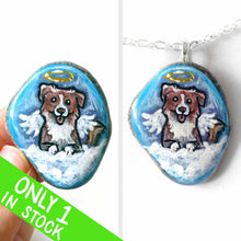 Load image into Gallery viewer, a small beach stone, hand painted with the portrait of a smiling Australian Shepherd dog, as an angel with wings and halo, sitting on fluffy clouds against a blue sky. this piece is available as a stone keepsake or pendant necklace
