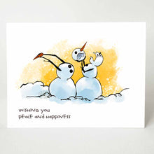 Load image into Gallery viewer, greeting card with an illustration of two snowmen in what looks like a middle of a fight. the right snowman has pulled off the other's head, while the left snowman (now headless) holds on to the right snowman's carrot nose. the card reads, "wishing you peace and happiness"
