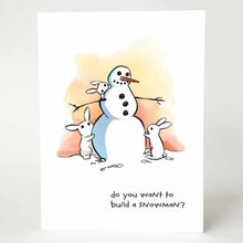 Load image into Gallery viewer, greeting card with an illustration of a smiling snowman with three small white rabbits helping to build it. on the bottom, the card says, "do you want to build a snowman?"
