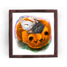 Load image into Gallery viewer, an art print featuring an illustration of a black cat and white cat napping together in a blanket shaped like a jack o'lantern
