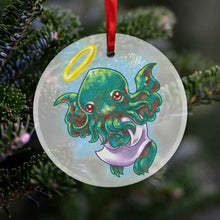 Load image into Gallery viewer, a round glass ornament, printed with an illustration of cthulhu as an angel, with a purple robe, and halo
