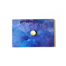 Load image into Gallery viewer, back of a blue and purple wood magnet, with a small circular magnet in the center. at the top reads "RainbowofCrazy"
