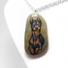 Load image into Gallery viewer, a beach stone hand painted with a portrait of a smiling doberman dog
