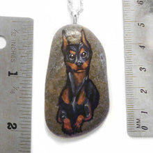 Load image into Gallery viewer, a beach stone hand painted with a portrait of a smiling doberman dog
