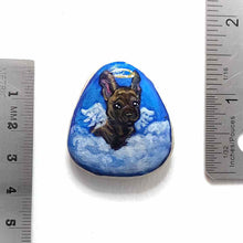 Load image into Gallery viewer, a small beach stone, hand painted with a portrait of a brindle french bulldog, as an angel in the clouds.
