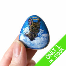 Load image into Gallery viewer, a small beach stone, hand painted with a portrait of a brindle french bulldog, as an angel in the clouds.
