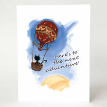 Load image into Gallery viewer, a greeting card with an illustration of a black cat in a hot air balloon, floating in the sky with the sun partially in view on the bottom right. the front of the card reads "Here's to the next adventure!"
