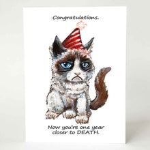 Load image into Gallery viewer, a greeting card, illustrated with a grumpy cat wearing a birthday hat. the front reads, "Congratulations. Now you're one year closer to DEATH."
