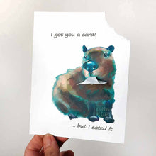Load image into Gallery viewer, a greeting card illustrated with a capybara. the top right corner of the card has been ripped out and hangs from the capybara's mouth. the card says "I got you a card! .. but I eated it"
