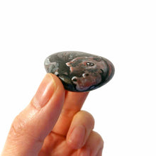 Load image into Gallery viewer, a hand holding a smooth, flat, beach stone hand painted with a smiling hippo
