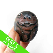 Load image into Gallery viewer, a small beach stone painted to looke like a smiling baby hippo
