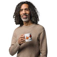 Load image into Gallery viewer, Person holding a 15 oz white ceramic mug, printed with art of two maple leaves with happy faces, and the words. "I be-leaf in you"
