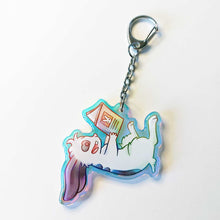 Load image into Gallery viewer, A clear, rainbow holographic acrylic keychain featuring a character from Rainbow of Crazy Comics: a smiling mini lop rabbit lounges on his back as he reads a book with a picture of a rabbit on the back.
