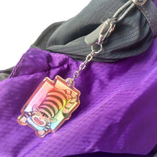 Load image into Gallery viewer, A clear, blue tinted holographic acrylic keychain featuring a character from Rainbow of Crazy Comics: a smiling tabby cat lounges in a cardboard box.
