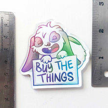 Load image into Gallery viewer, An acrylic magnet featuring a character from Rainbow of Crazy Comics: a mini lop rabbit smiles and holds up a sign that says "BUY THE THINGS", approximately 2.5" in size.

