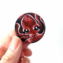 Load image into Gallery viewer, a lightweight wood disc, hand painted with a portrait of a red baby octopus. the painting is available as a keepsake, or pendant necklace
