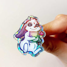 Load image into Gallery viewer, A glittery acrylic pin featuring a character from Rainbow of Crazy Comics: a mini lop rabbit hugging a book, with a tiny heart next to him.

