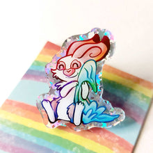 Load image into Gallery viewer, A glittery acrylic pin featuring a character from Rainbow of Crazy Comics: Linus an English spot rabbit, smiles as he cuddles a light blue blanket.
