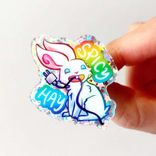 Load image into Gallery viewer, A glittery acrylic pin featuring a character from Rainbow of Crazy Comics: a smiling white rabbit holding a charging cable in her mouth, with the words "SPICY HAY in rainbow colours.
