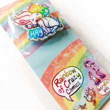 Load image into Gallery viewer, A glittery acrylic pin featuring a character from Rainbow of Crazy Comics: a smiling white rabbit holding a charging cable in her mouth, with the words "SPICY HAY in rainbow colours. packaged with a backing board featuring more Rainbow of Crazy Comic characters
