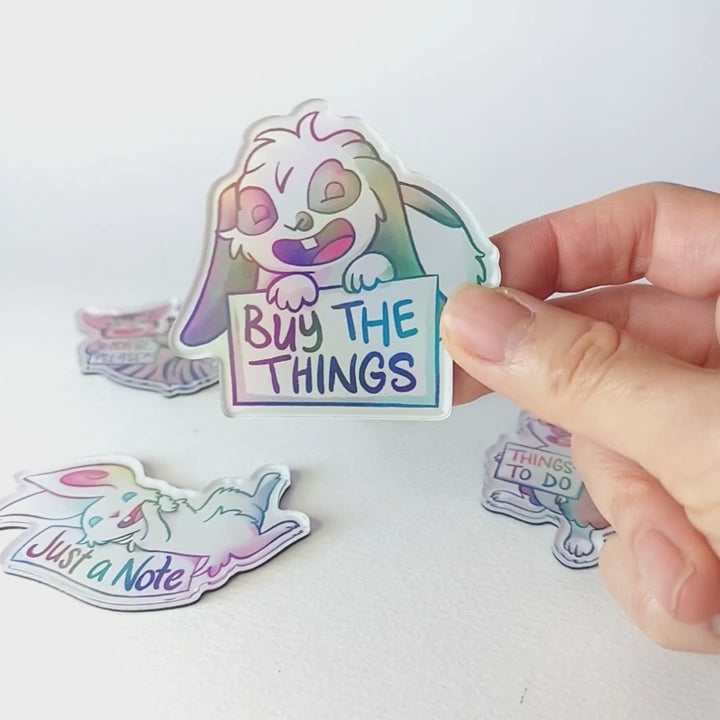 Video of a hand tilting the mini lop rabbit magnet back and forth to showcase the holographic finish.