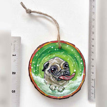 Load image into Gallery viewer, a wood ornament, hand painted with a pug in the snow, tongue out, ready to catch snowflakes
