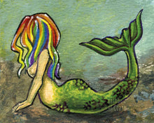 Load image into Gallery viewer, A colorful artwork of a mermaid with bright rainbow hair lying on the ocean floor, arching her back, and raising her tail.
