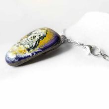 Load image into Gallery viewer, a beach stone hand painted with a sheepdog, as an angel with a halo, sitting on clouds against a purple and yellow sky. available as a keepsake or pendant necklace
