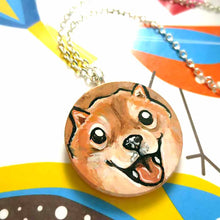 Load image into Gallery viewer, small wood disc painted with a smiling Shiba inu's face. available as a keepsake or pendant necklace 
