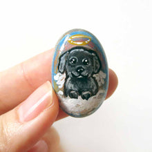 Load image into Gallery viewer, A small beach stone, hand painted with a portrait of a black shih tzu dog as an angel sitting in the clouds. Available as a keepsake, fridge magnet, or necklace
