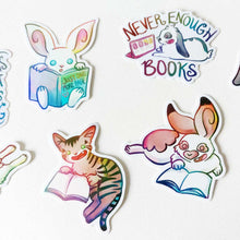 Load image into Gallery viewer, A variety of colorful stickers with cat and rabbit characters from Rainbow of Crazy Comics, each are enjoying books. One sticker shows a rabbit looking at a table, the sticker says "never enough books"
