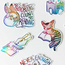 Load image into Gallery viewer, A variety of colorful stickers with cat and rabbit characters from Rainbow of Crazy Comics, each are enjoying books. One sticker shows a rabbit with headphones and the text "AUDIOBOOKS COUNT AS READING".
