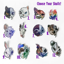 Load image into Gallery viewer, A set of 12 animal skull sticker designs numbered 1 to 12, with the text 'Choose Your Skulls!' at the top right. 1) Black cat. 2) White cat. 3) Smiling, cartoon tabby cat. 4) Comic Jo with red eyes, with a deer skull on her head. 5) chinchilla. 6) unicorn. 7) sloth. 8) otter. 9) white rabbit. 10) ferret. 11) owl. 12) possum.
