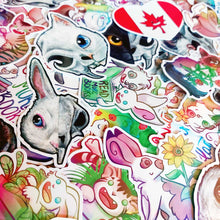 Load image into Gallery viewer, A pile of colourful cartoon and animal stickers, including rabbits, a white cat skull, a Canadian flag heart sticker, flowers, and text stickers, filling the frame.
