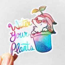 Load image into Gallery viewer, sticker featuring an english spot rabbit (from Rainbow of Crazy Comics) in a plant pot. a seedling sits on top of the rabbit's head. the sticker has the words "Water Your Plants".
