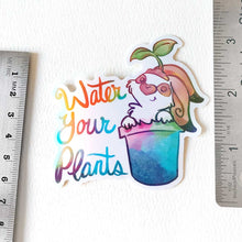 Load image into Gallery viewer, sticker featuring an english spot rabbit (from Rainbow of Crazy Comics) in a plant pot. a seedling sits on top of the rabbit's head. the sticker has the words "Water Your Plants".

