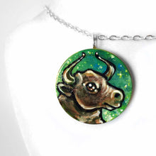 Load image into Gallery viewer, wood pendant hand painted with a bull (taurus) against a starry green background

