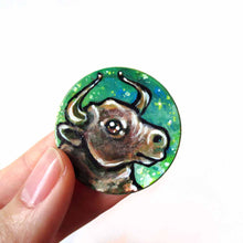 Load image into Gallery viewer, wood disc hand painted with a bull (taurus) against a starry green background
