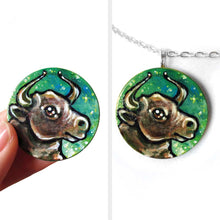 Load image into Gallery viewer, wood pendant hand painted with a bull (taurus) against a starry green background
