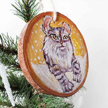 Load image into Gallery viewer, A wooden ornament with art of an American Curl cat with golden eyes, watching the snow fall
